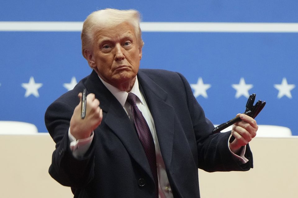 President Donald Trump throws pens used to sign executive orders to the crowd during an indoor Presidential Inauguration parade event (AP/Matt Rourke)