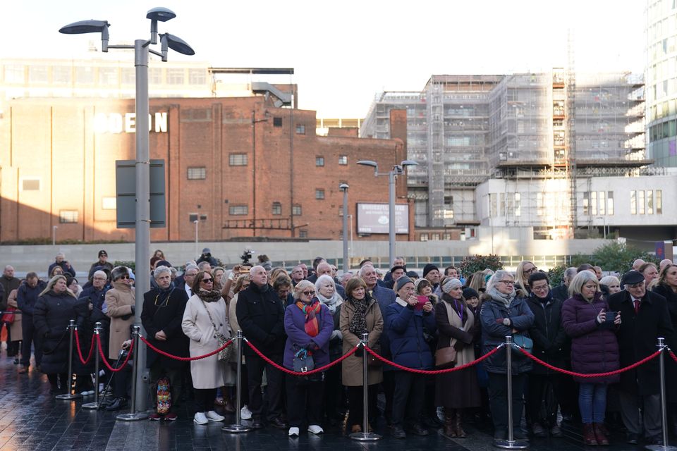 Members of the public watch the memorial service in 1,000 Trades Square (Jacob King/PA)