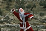 thumbnail: A Palestinian demonstrator dressed as Santa Claus uses a sling-shot to hurl stones at Israeli border police during a demonstration against Israel's separation barrier in the West Bank village of Bilin near Ramallah, Friday, Dec. 26, 2008. Israel says the barrier is necessary for security while Palestinians call it a land grab.(AP Photo/Muhammed Muheisen)