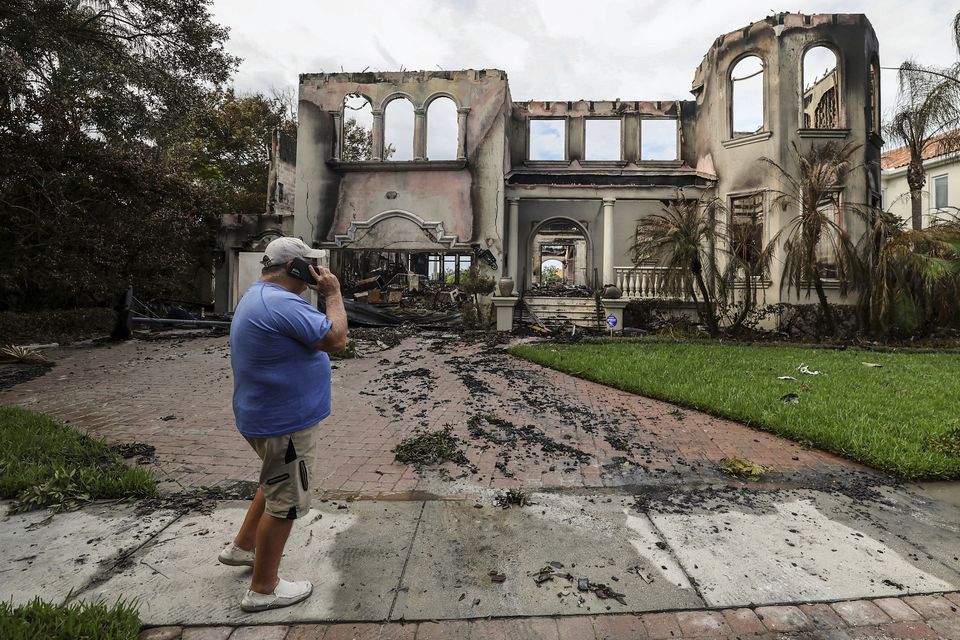 Joe Daum looks at the remains of a friend’s home that burned during Hurricane Helene on Davis Island, Tampa, Florida (Mike Carlson/AP/PA)