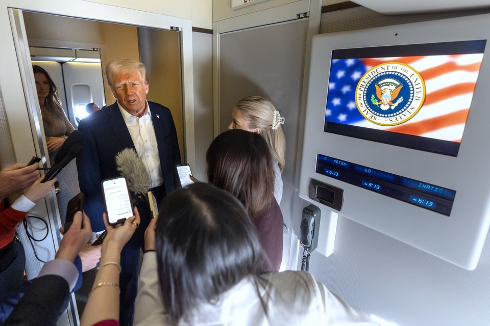 Donald Trump speaks to reporters aboard Air Force One (Mark Schiefelbein/AP)