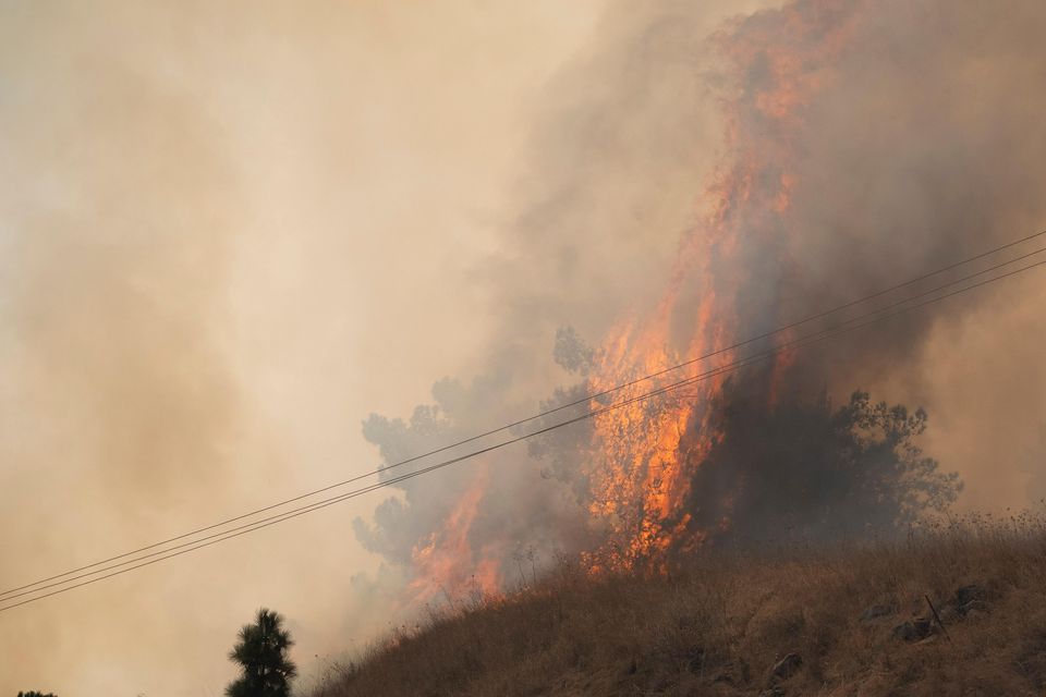 Members of the Israeli forces watch a fire after a rocket, fired from Lebanon, hit an area near the town of Rosh Pinna in northern Israel (Leo Correa/AP)