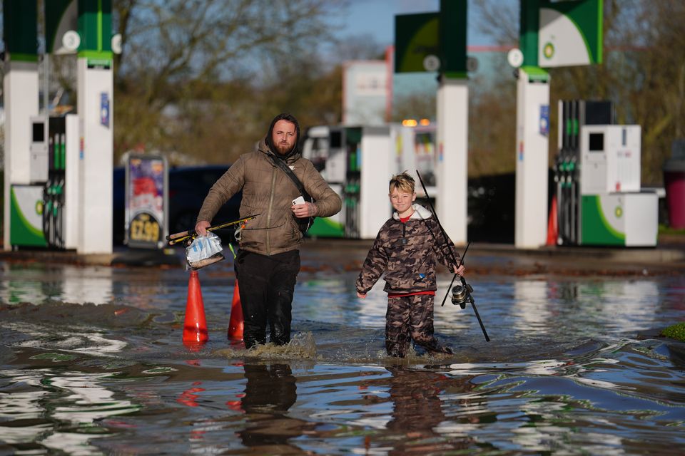 People walk through floodwater near the Billing Aquadrome in Northamptonshire (Jordan Pettitt/PA)