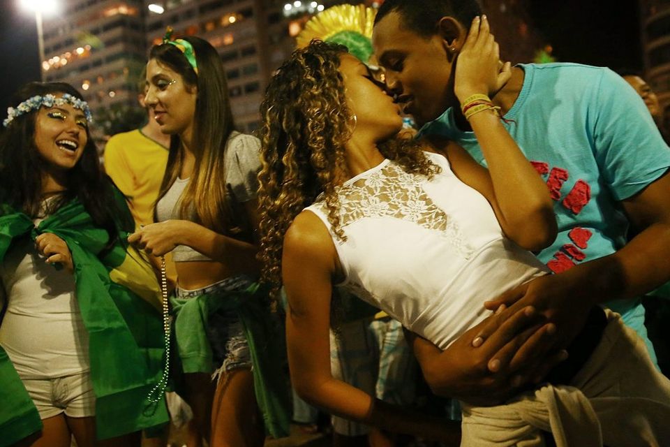 RIO DE JANEIRO, BRAZIL - JUNE 23:  A couple kisses after Brazil defeated Cameroon during celebrations along Copacabana Beach on June 23, 2014 in Rio de Janeiro, Brazil. Brazil won the match 4-1.  (Photo by Mario Tama/Getty Images)