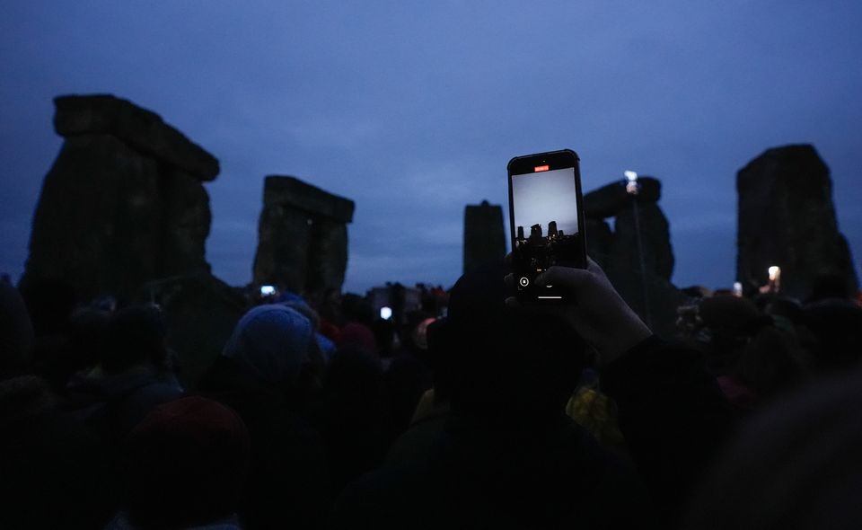 A person films on their phone as people take part in the winter solstice celebrations (Andrew Matthews/PA)