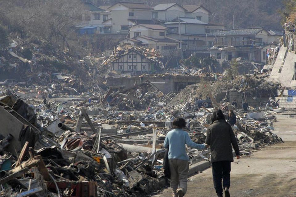 A couple walk along the rubble at a residential area in Onagawa, Miyagi Prefecture, northern Japan, Sunday, March 13, 2011, two days after a powerful earthquake-triggered tsunami hit the country's east coast. (AP Photo/The Yumiuri Shimbun) JAPAN OUT, CREDIT MANDATORY