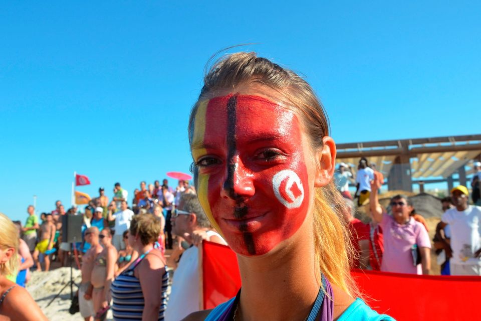 A tourist with the Tunisian flag painted on her face takes part in a gathering in solidarity with Tunisia's tourism industry, on June 29, 2015 on the island of Djerba. Tunisia said it had made its first arrests after a beach massacre that killed 38 people, as European officials paid tribute to victims of the country's worst jihadist attack. AFP PHOTO / FETHI NASRIFETHI NASRI/AFP/Getty Images