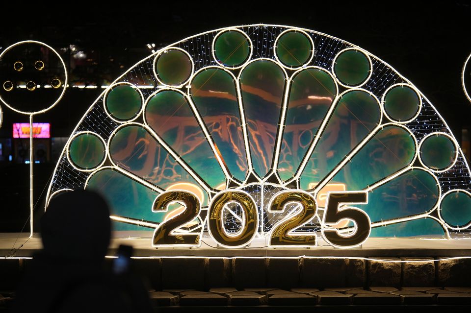 A woman holds her smartphone near an illuminated decoration in Seoul, South Korea (Lee Jin-man/AP)