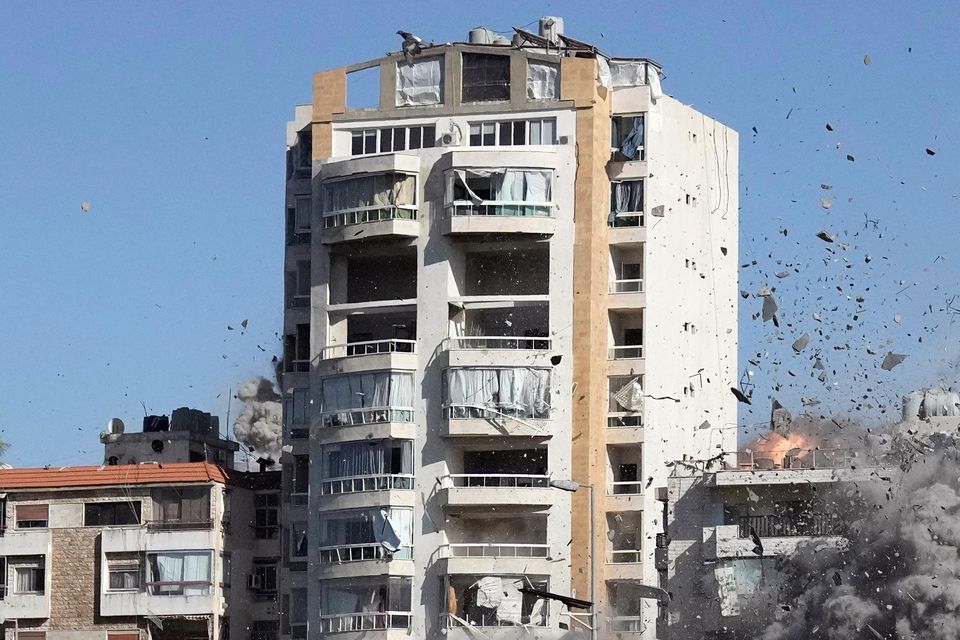 People watch a building collapse after being hit by an Israeli airstrike in Ghobeiri, Beirut (Bilal Hussein/AP)