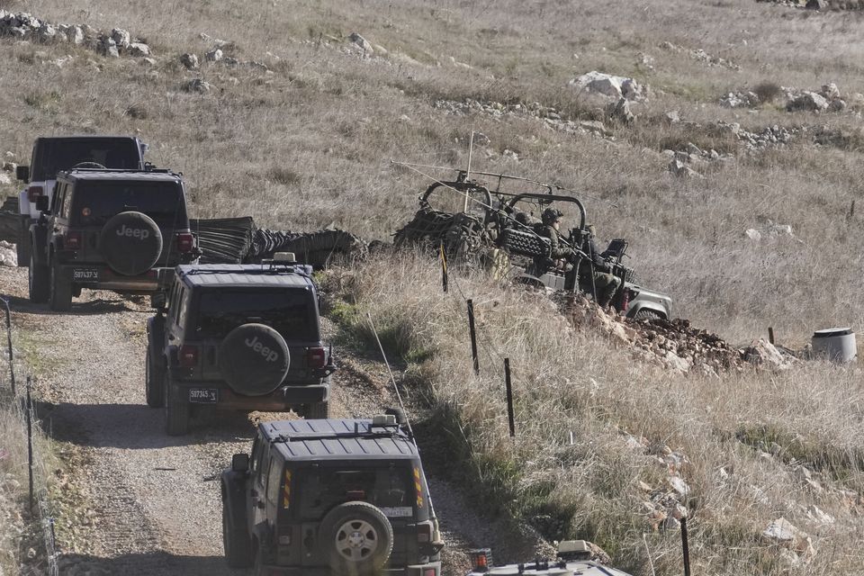 Israeli armoured vehicles cross the security fence moving towards the so-called Alpha Line that separates the Israeli-annexed Golan Heights from Syria (Matias Delacroix/AP)