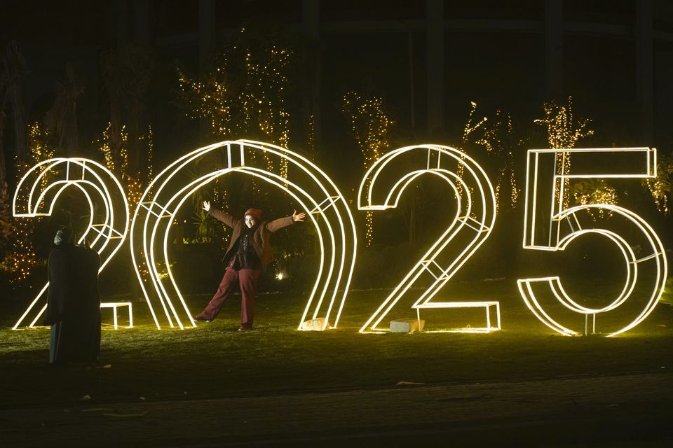 An Egyptian poses in front of new year decorations in Cairo, Egypt (Amr Nabil/AP)