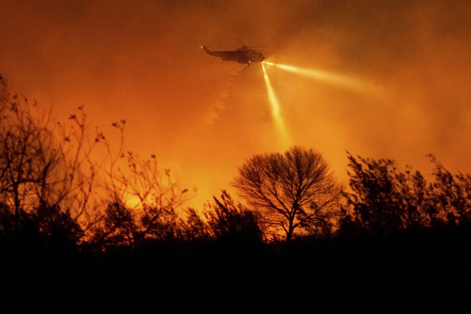 A helicopter drops water while fighting the Auto Fire in Ventura County (Noah Berger/AP)