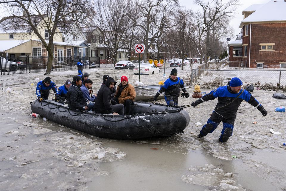 Members of the Southeast Michigan Dive Team pull people to safety after a water main break in Detroit caused massive flooding (Andy Morrison/Detroit News via AP)