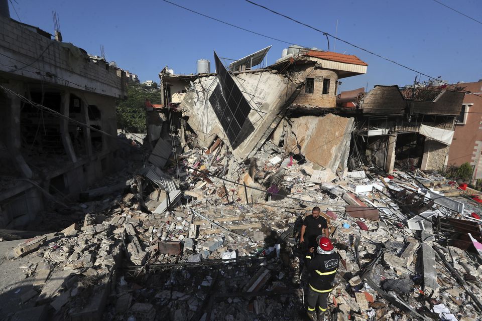 Rescuers stand on the rubble of a building hit in an Israeli airstrike in the southern village of Akbieh, Lebanon (Mohammed Zaatari/AP)