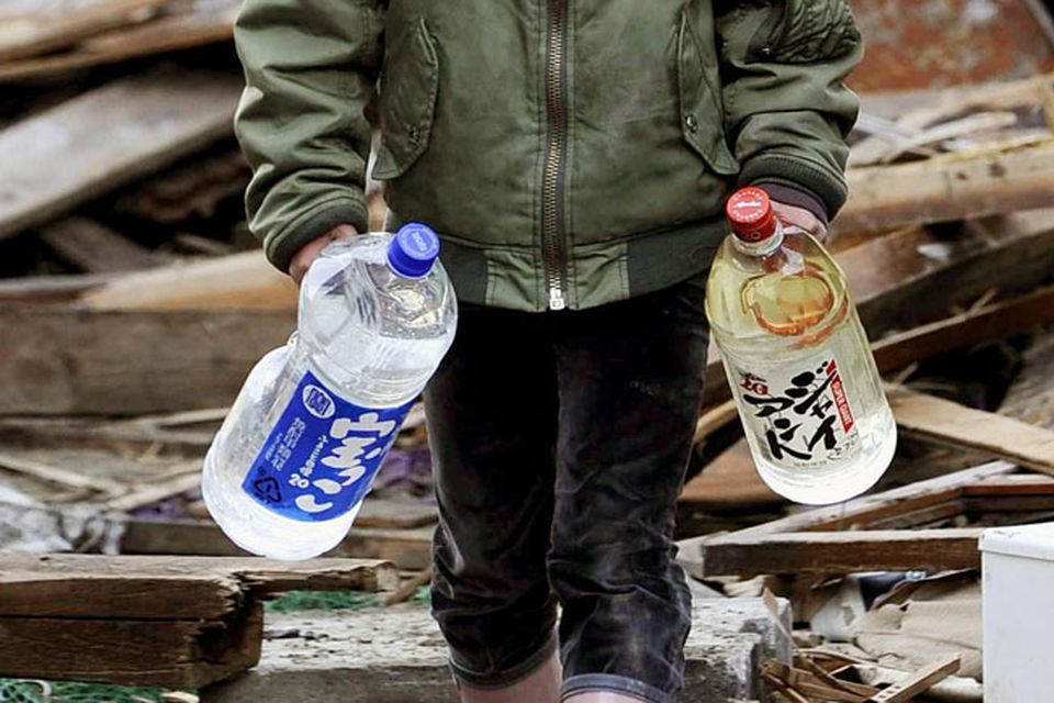 Boy carries bottles of water amid debris in Kesennuma, northern Japan Monday, March 14, 2011 following Friday's massive earthquake and the ensuing tsunami. (AP Photo/Kyodo News) JAPAN OUT, MANDATORY CREDIT, NO SALES IN CHINA, HONG  KONG, JAPAN, SOUTH KOREA AND FRANCE, CORRECTS DATE PHOTO TAKEN