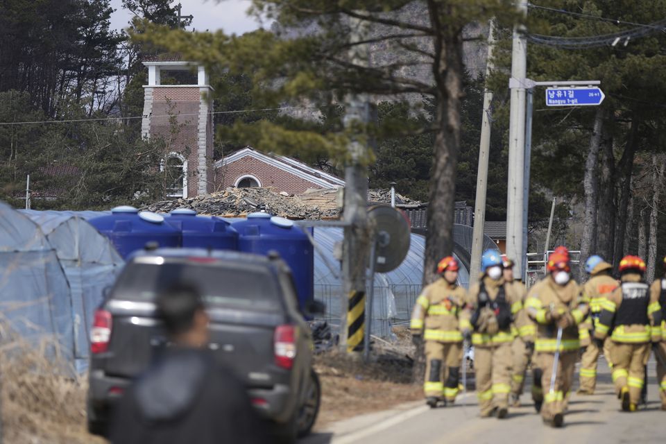 Firefighters survey the damage (Lee Jin-man/AP)