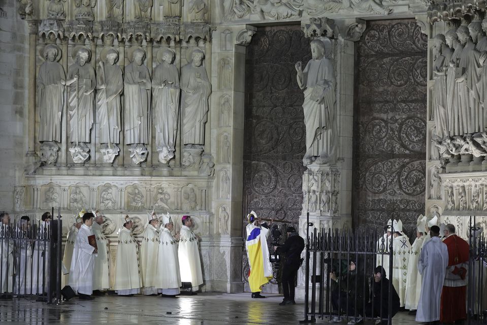 Paris’ archbishop Laurent Ulrich knocks on the doors of the cathedral to mark its reopening (Teresa Suarez, Pool via AP)