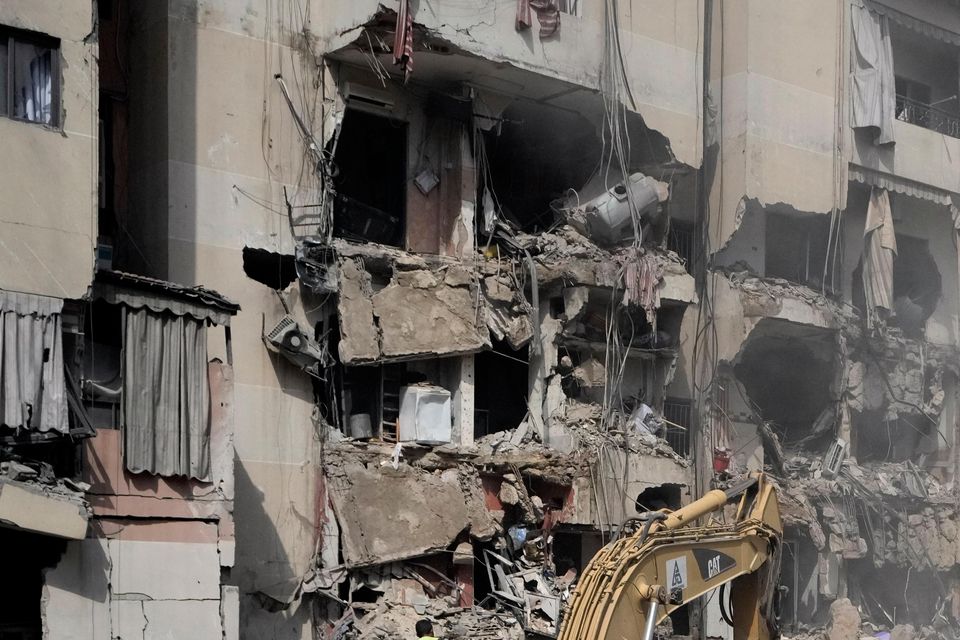 Excavators are used to clear rubble at the site of Friday’s Israeli strike (Bilal Hussein/AP)