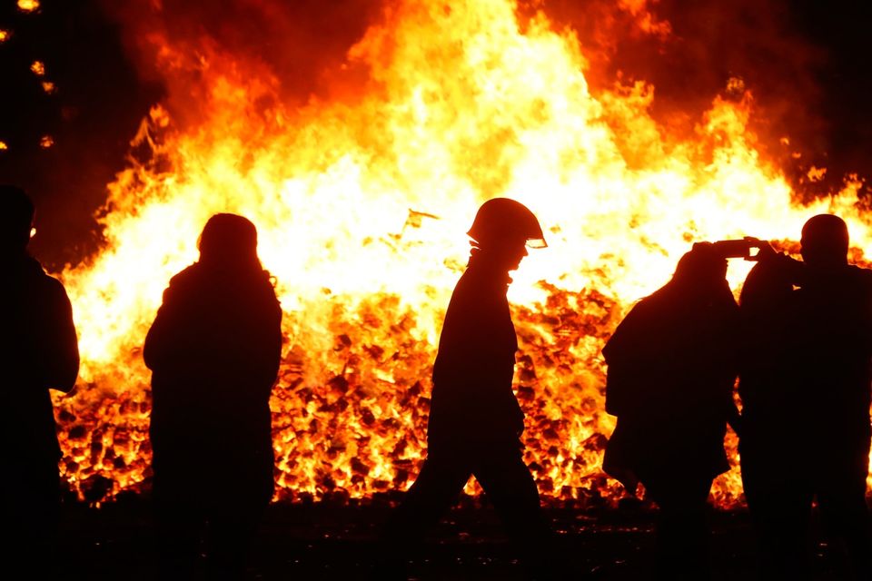A firefighter attends to  an 11th night Bonfire in the Sandy Row area of Belfast. Pic: Niall Carson/PA Wire