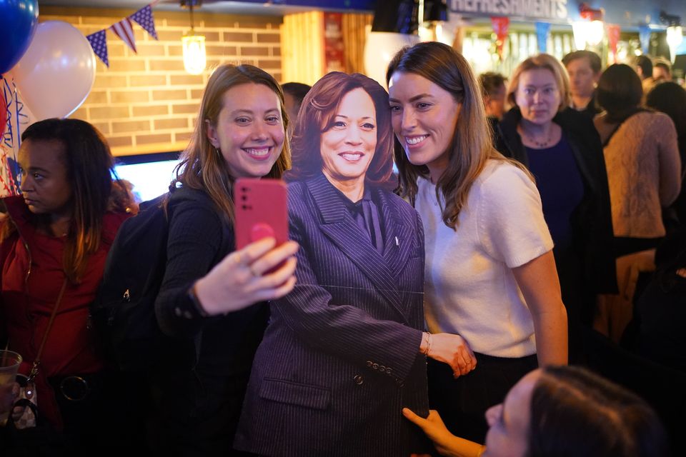 People pose for photos with a cardboard cutout of Kamala Harris at the Democrats Abroad US election-watching event in central London (PA)