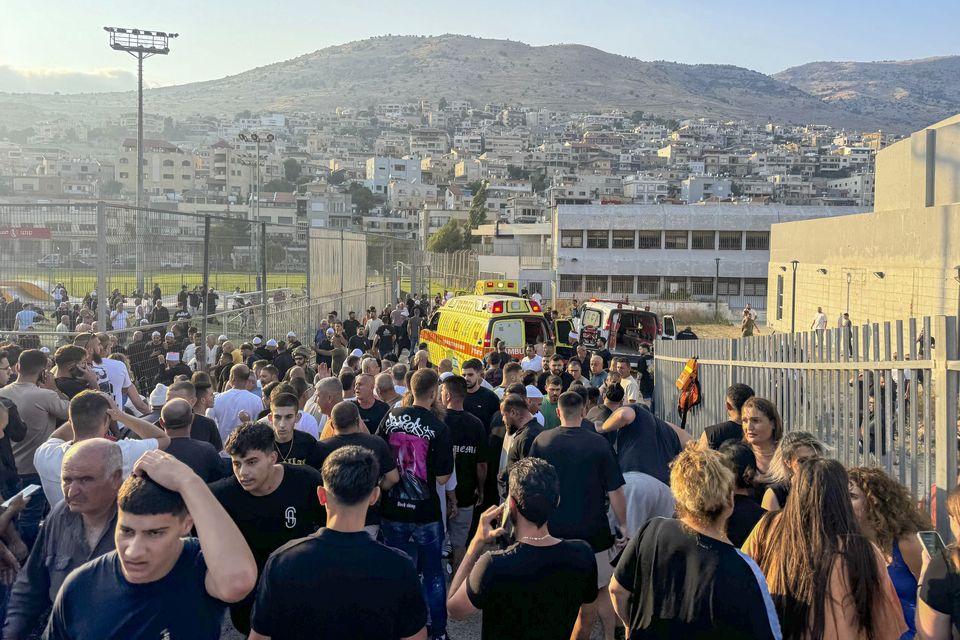 Residents and paramedics rushed to help children after a rocket hit a football field in the Golan Heights (Hassan Shams/AP)