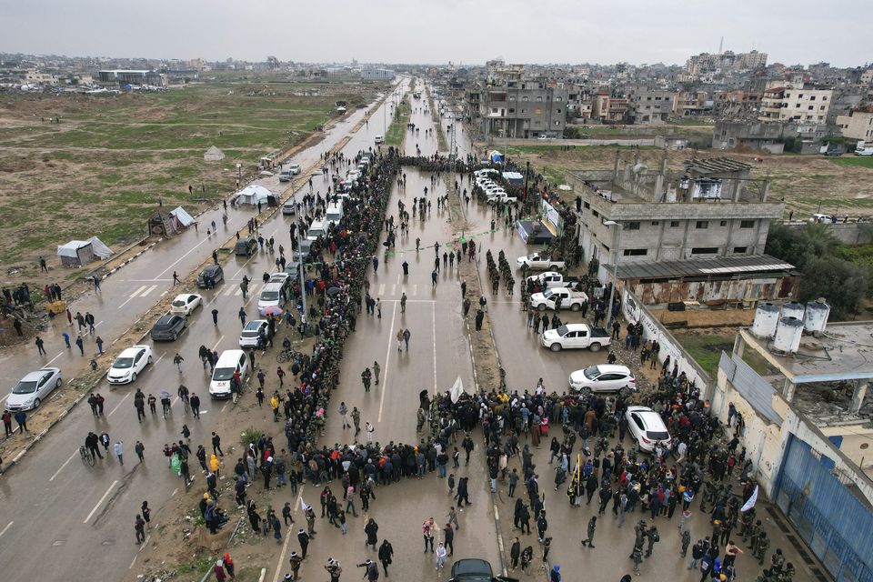 Palestinians gather as Hamas fighters prepare for the planned release of Israeli hostages set to be handed over to the Red Cross in Nuseirat, central Gaza (Mohammad Abu Samra/AP)