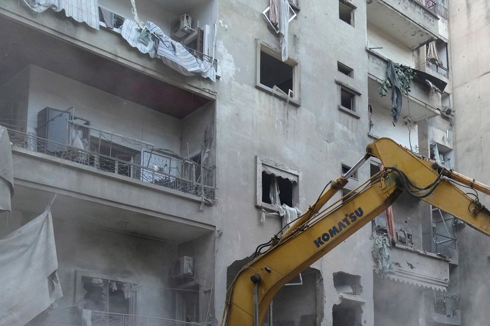 Rescue workers use an excavator to clear the rubble of destroyed buildings as they search for victims of an Israeli airstrike in Beirut (AP Photo/Hussein Malla)