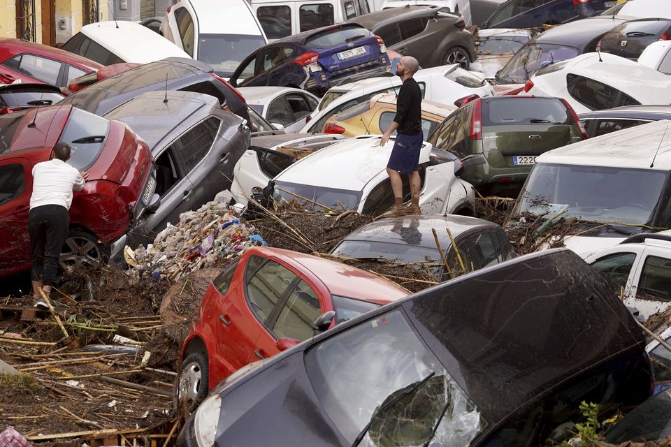 Residents look at cars piled up after being swept away by floods in Valencia (Alberto Saiz/AP)