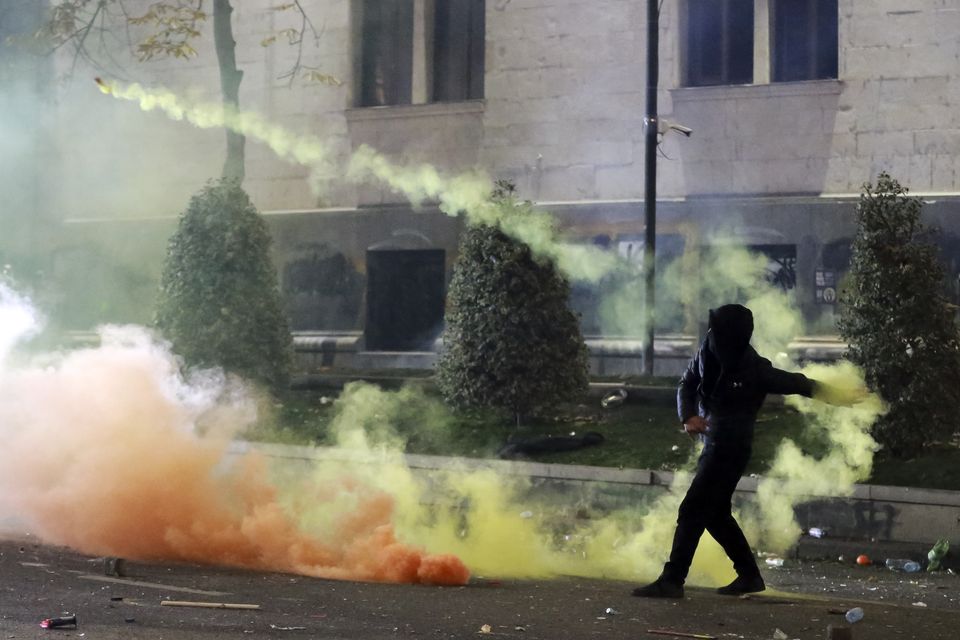 A demonstrator throws a firecracker toward police as officers block a street to halt protesters outside the parliament building in Tbilisi (AP Photo/Zurab Tsertsvadze)