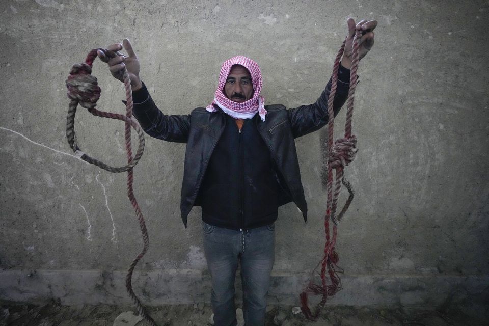 A man holds two ropes tied in the shape of nooses, found in the infamous Saydnaya military prison (Hussein Malla/AP)