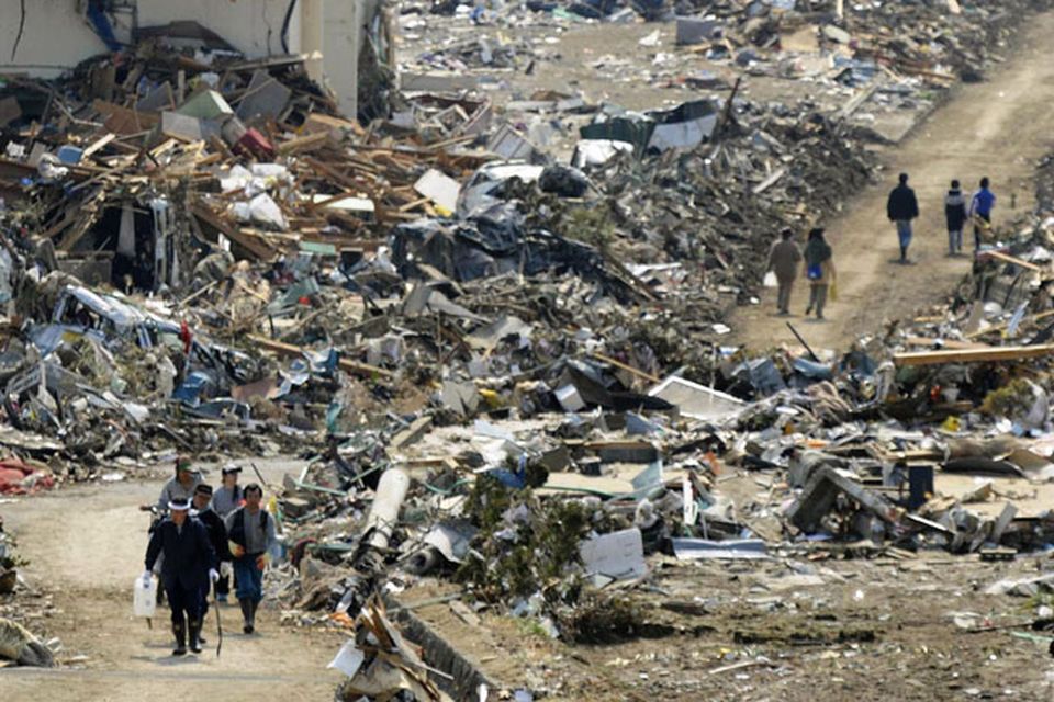 People walk amid the rubble in Rikuzentakata, Iwate prefecture, northern Japan, Sunday, March 13, 2011, two days after the powerful earthquake-triggered tsunami hit the country's east coast. (AP Photo/Kyodo News) JAPAN OUT, MANDATORY CREDIT, NO SALES IN CHINA, HONG  KONG, JAPAN, SOUTH KOREA AND FRANCE