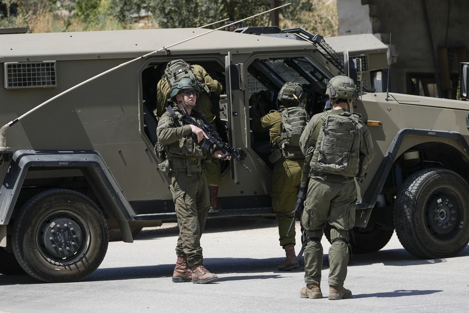 Israeli military officers gather by their vehicles in a refugee camp in the occupied West Bank (Majdi Mohammed/AP)