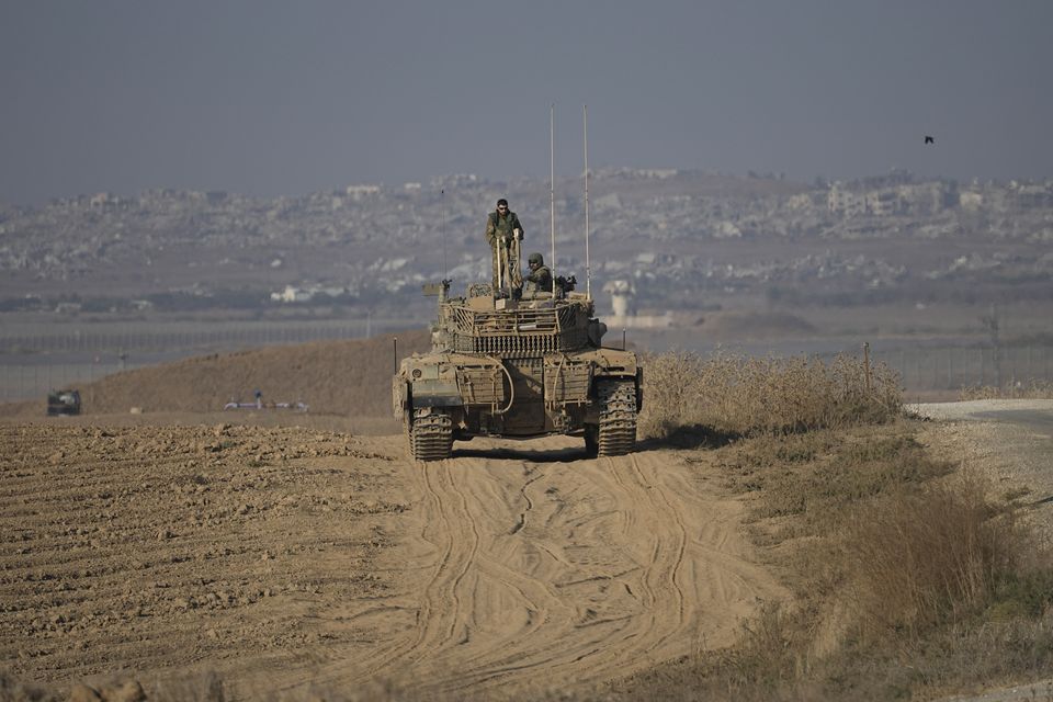 Israeli Defence Forces soldiers work on their tank near the Israel-Gaza border, as seen from southern Israel (Tsafrir Abayov/AP)