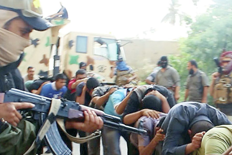 A member of Isis points a gun at captured Iraqi soldiers in plain clothes
