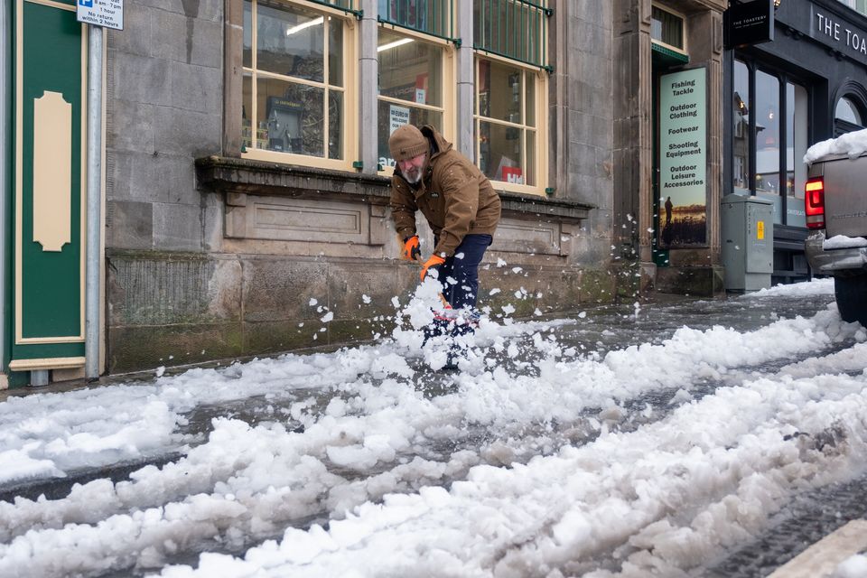 Graham Thompson clearing the snow from the shop front of Home Field and Stream, Enniskillen. Image: Andrew Paton/PressEye