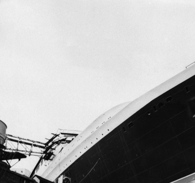 A group of young men play football beneath the hull of the QE2 in a shipyard in Clydebank, Scotland, in 1967 ( Mirrorpix/PA)