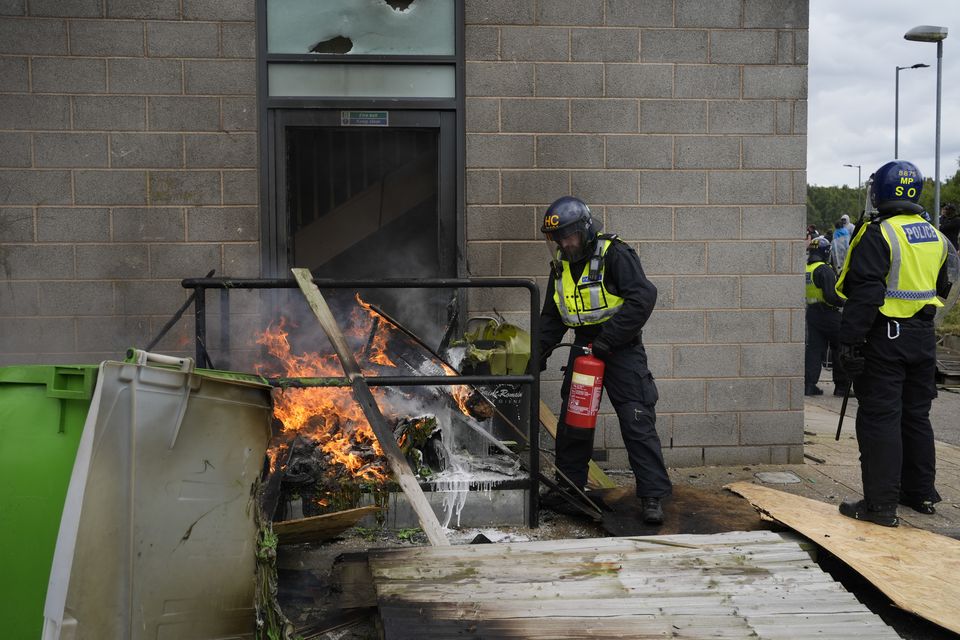 A fire is extinguished by police officers during the anti-immigration protest outside the Holiday Inn Express in Rotherham, South Yorkshire on August 4 (Danny Lawson/PA)