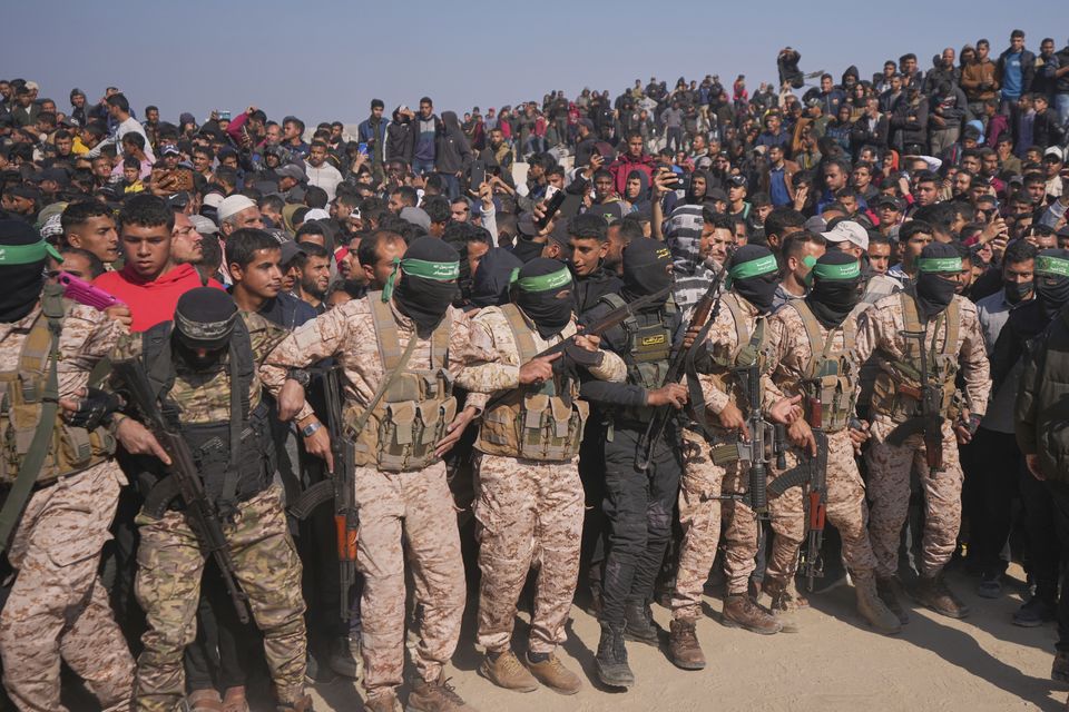 Hamas and Islamic Jihad fighters contain the crowd as cars carrying Israeli Gadi Mozes and Arbel Yahoud are escorted to be handed over to the Red Cross in Khan Younis (Abdel Kareem Hana/AP)