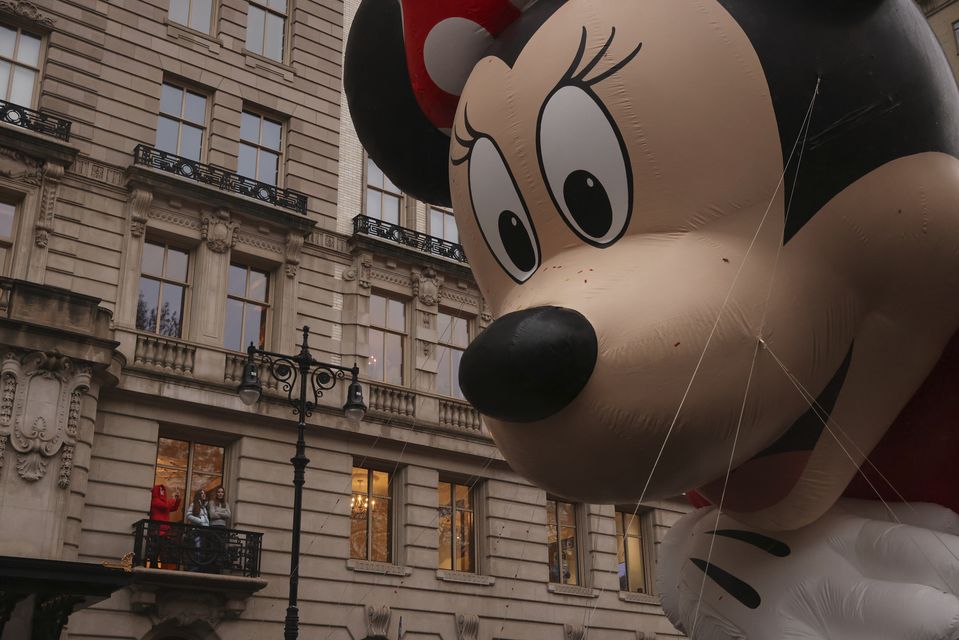 Spectators watch from an apartment balcony as Disney’s Minnie Mouse balloon floats by on Central Park West during the Macy’s Thanksgiving Day Parade (Yuki Iwamura/AP)