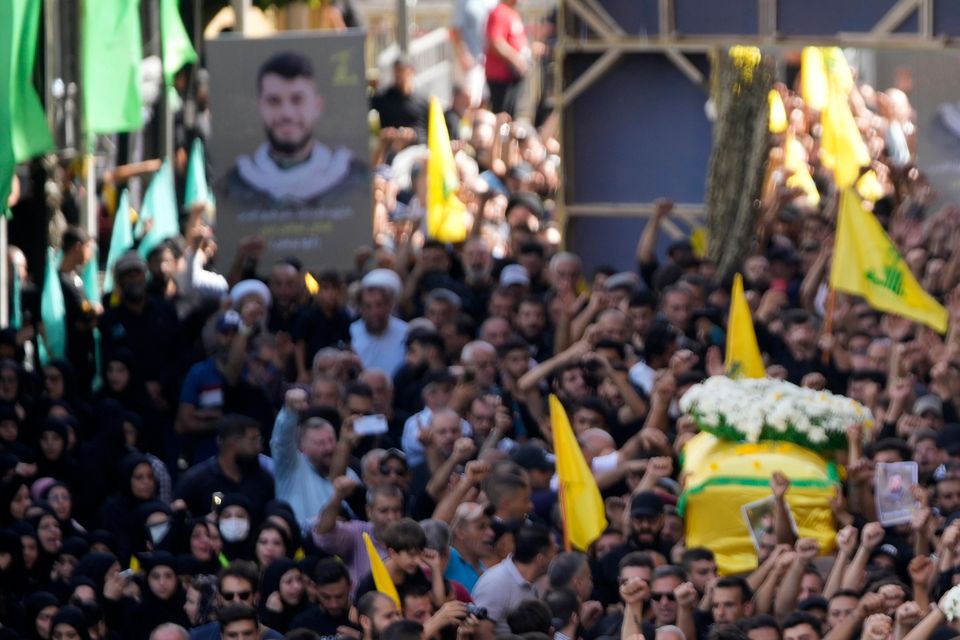 Hezbollah members carry the coffins of their comrades who were killed on Wednesday during a funeral procession in the southern suburbs of Beirut (Hussein Malla/AP)