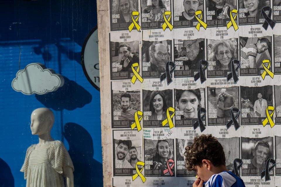 A boy walks past a wall with photos of hostages held in the Gaza Strip, in Tel Aviv (Ariel Schalit/AP/PA)