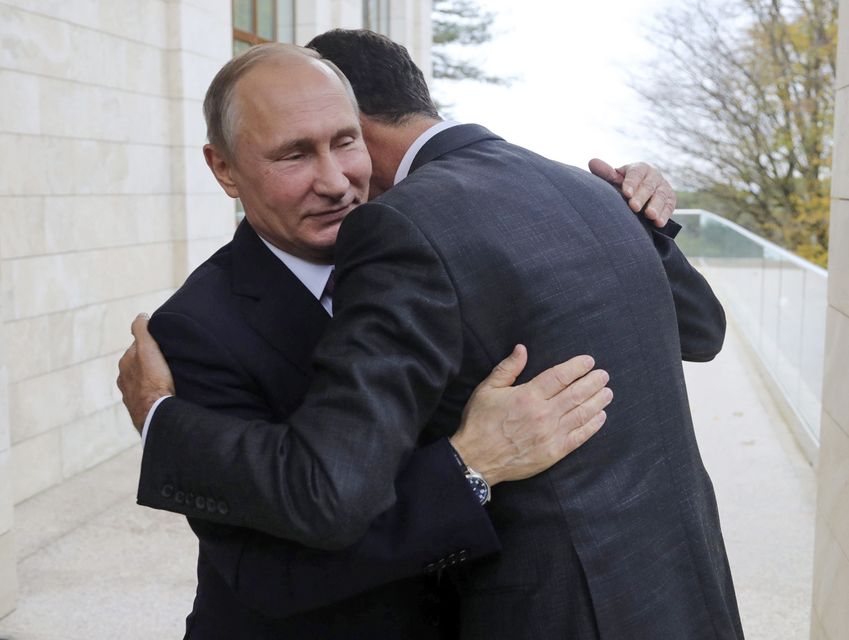 Mr Assad and Russian President Vladimir Putin embrace during a meeting in Sochi, Russia, in November 2017 (Mikhail Klimentyev/ Kremlin pool/AP)