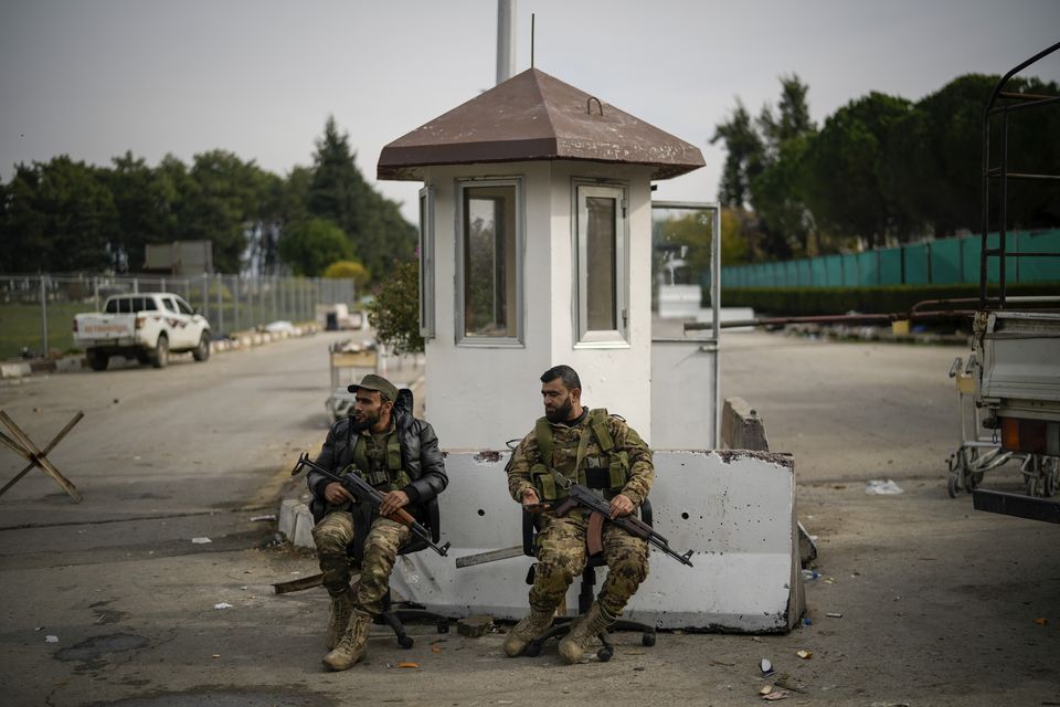 Syrian fighters guard the entrance of the Latakia civilian airport in the town of Hmeimim (Leo Correa/AP)