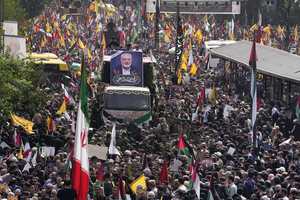 Iranians follow a lorry carrying the coffins of Hamas leader Ismail Haniyeh and his bodyguard in Tehran (Vahid Salemi/AP)