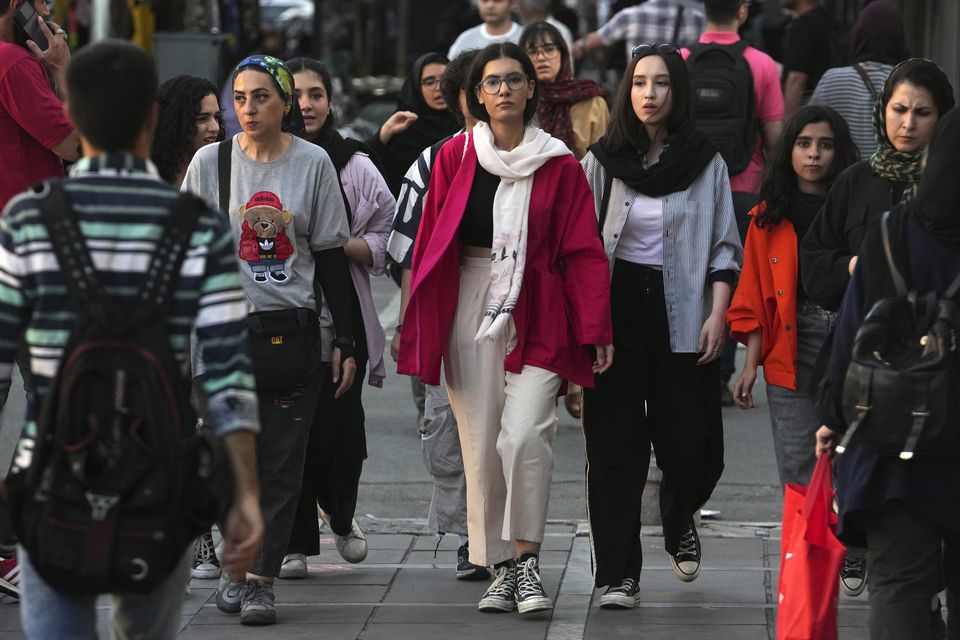 Iranian women, some without wearing their mandatory Islamic headscarves, walk in downtown Tehran (Vahid Salemi/AP)