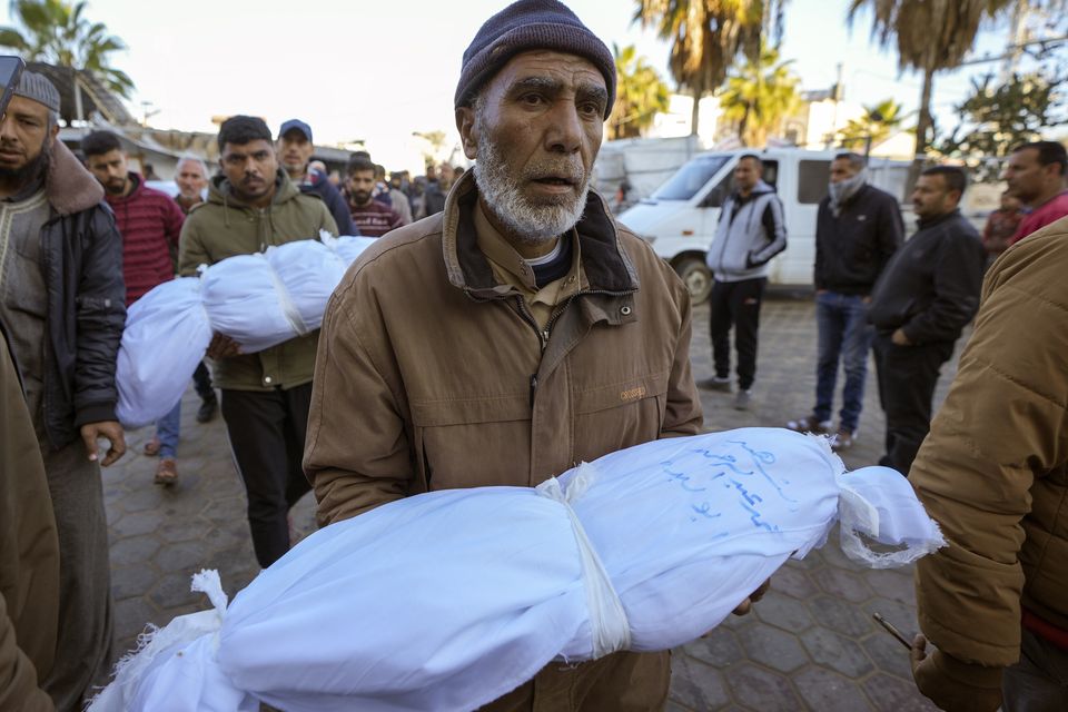 Abdallah Abu Libda carries the body of his six-month-old nephew as victims of overnight Israeli army strikes prepare for funeral prayers (Abdel Kareem Hana/AP)