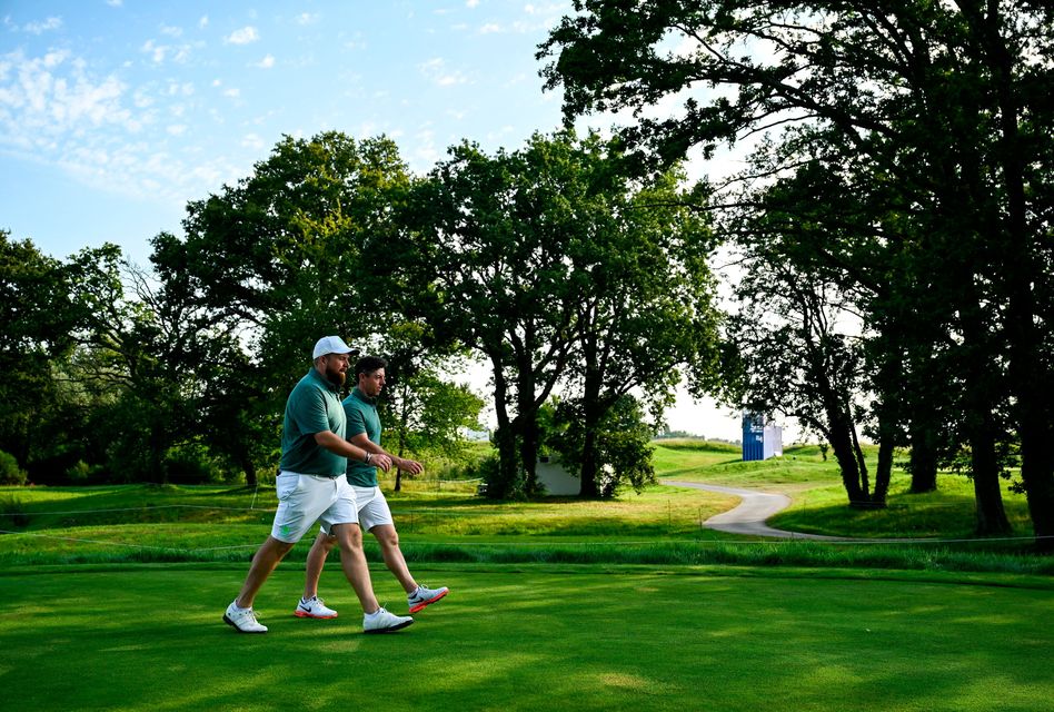 Shane Lowry, left, and Rory McIlroy of Team Ireland walk the course before a practice round.