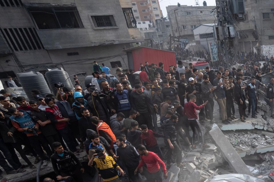 Palestinians search for bodies and survivors in the rubble of a residential building destroyed by an Israeli airstrike, in December (Fatima Shbair/AP)