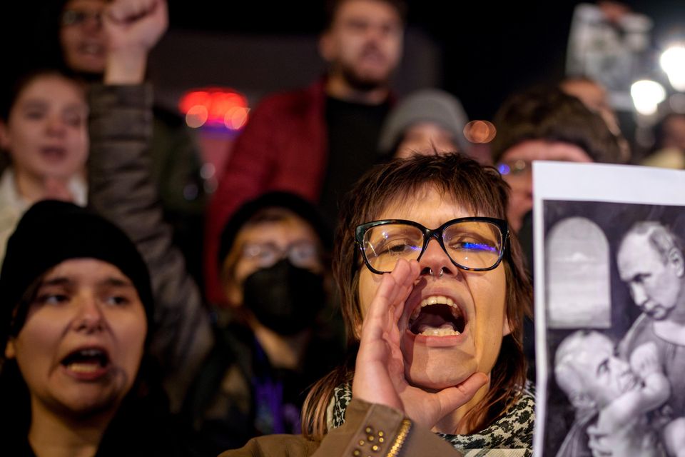 A woman shouts holding an altered version of a classic painting, depicting Russian President Vladimir Putin and Calin Georgescu, the independent candidate for Romanian presidency  (AP/Andreea Alexandru)