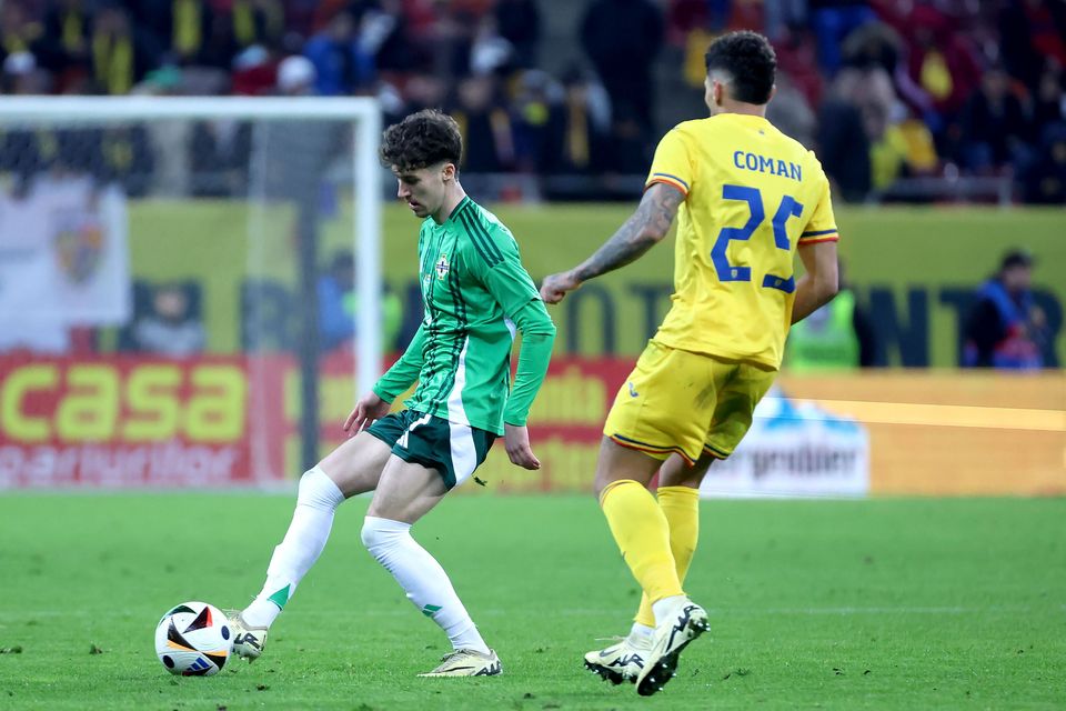 Northern Ireland's Trai Hume plays the ball out under pressure from Romania's Florinel Coman